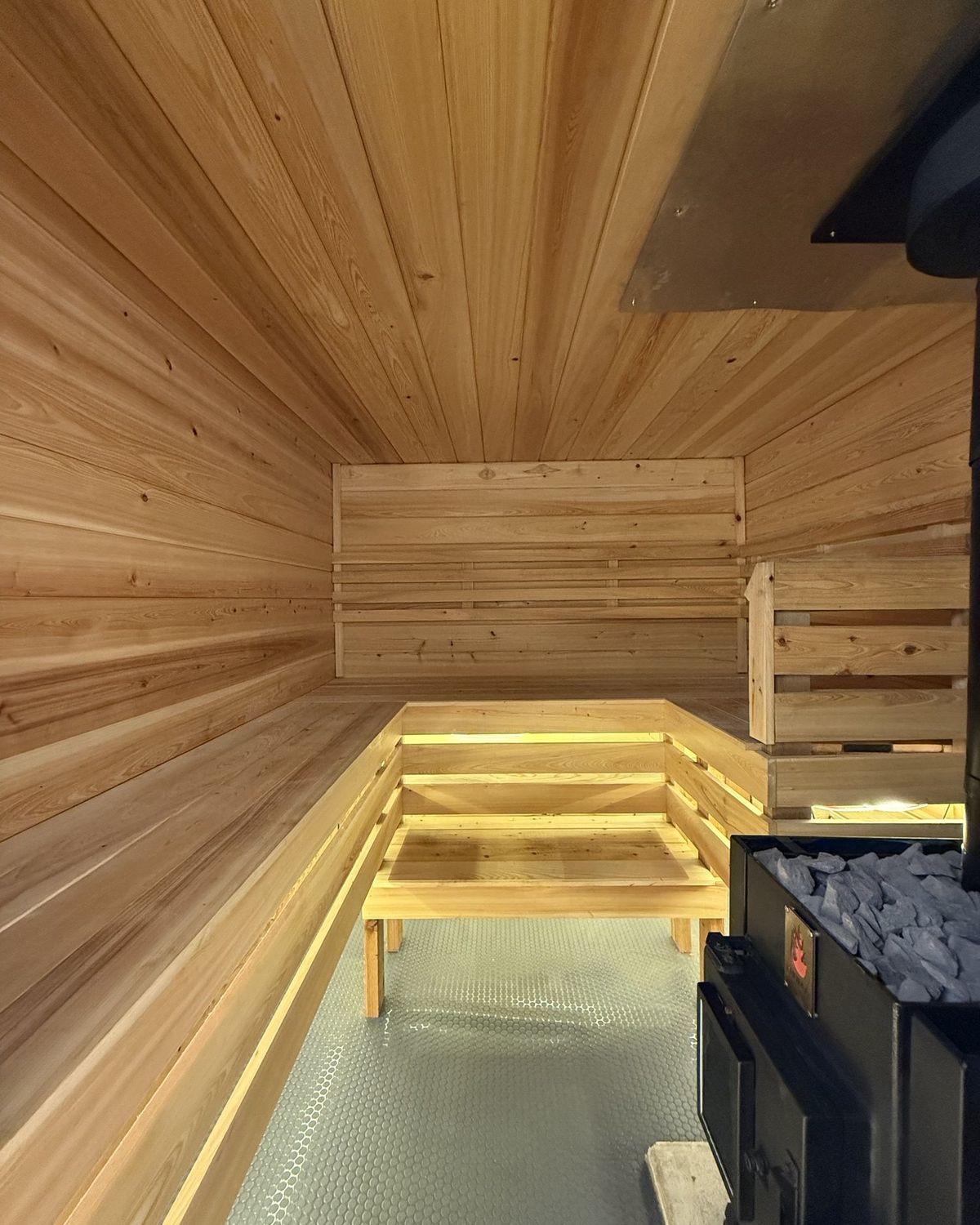 Hand-built cedar benches inside the Smoky Banya mobile sauna, lit by warm under-bench light