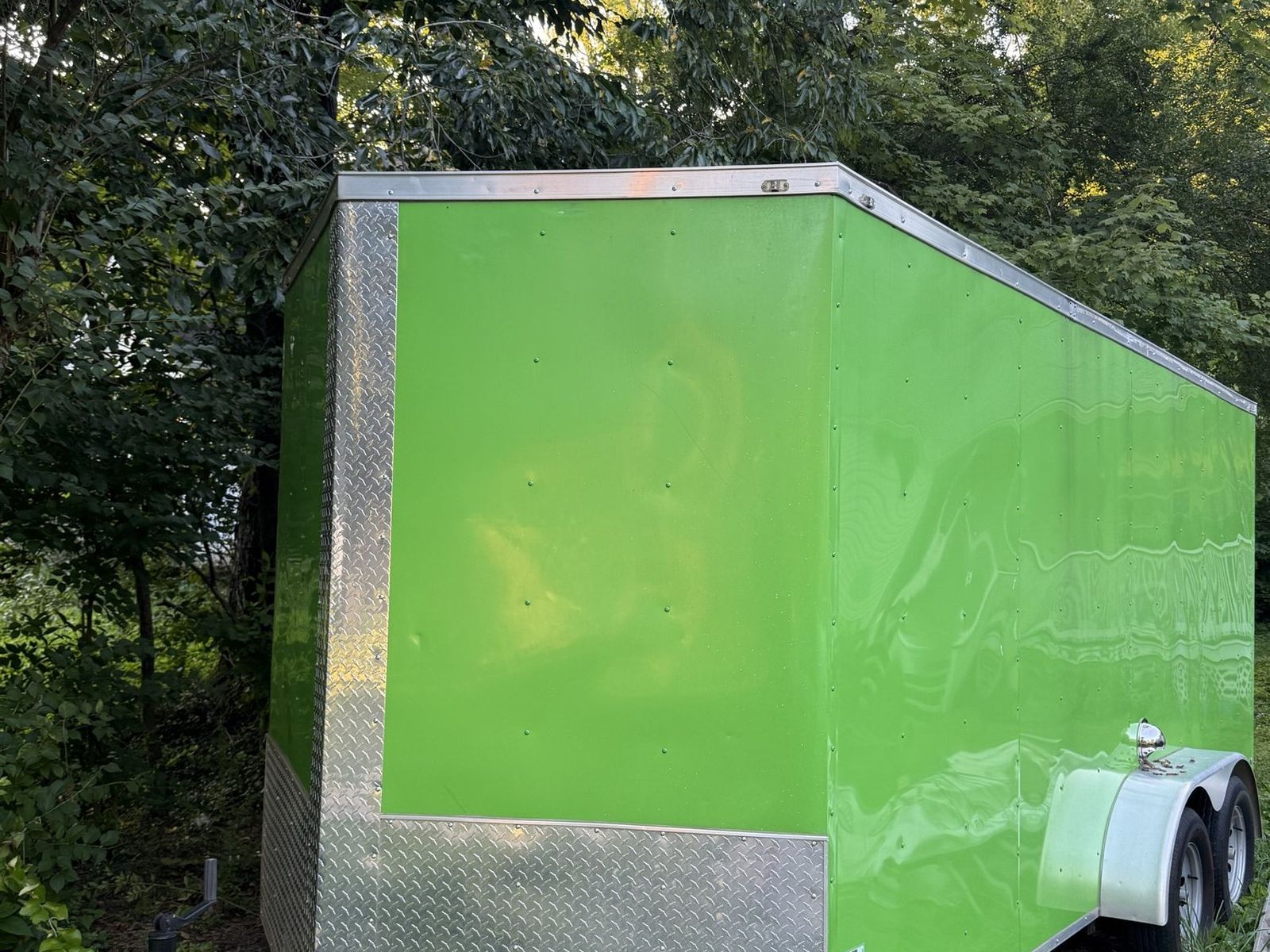 The green Smoky Banya sauna trailer parked among trees